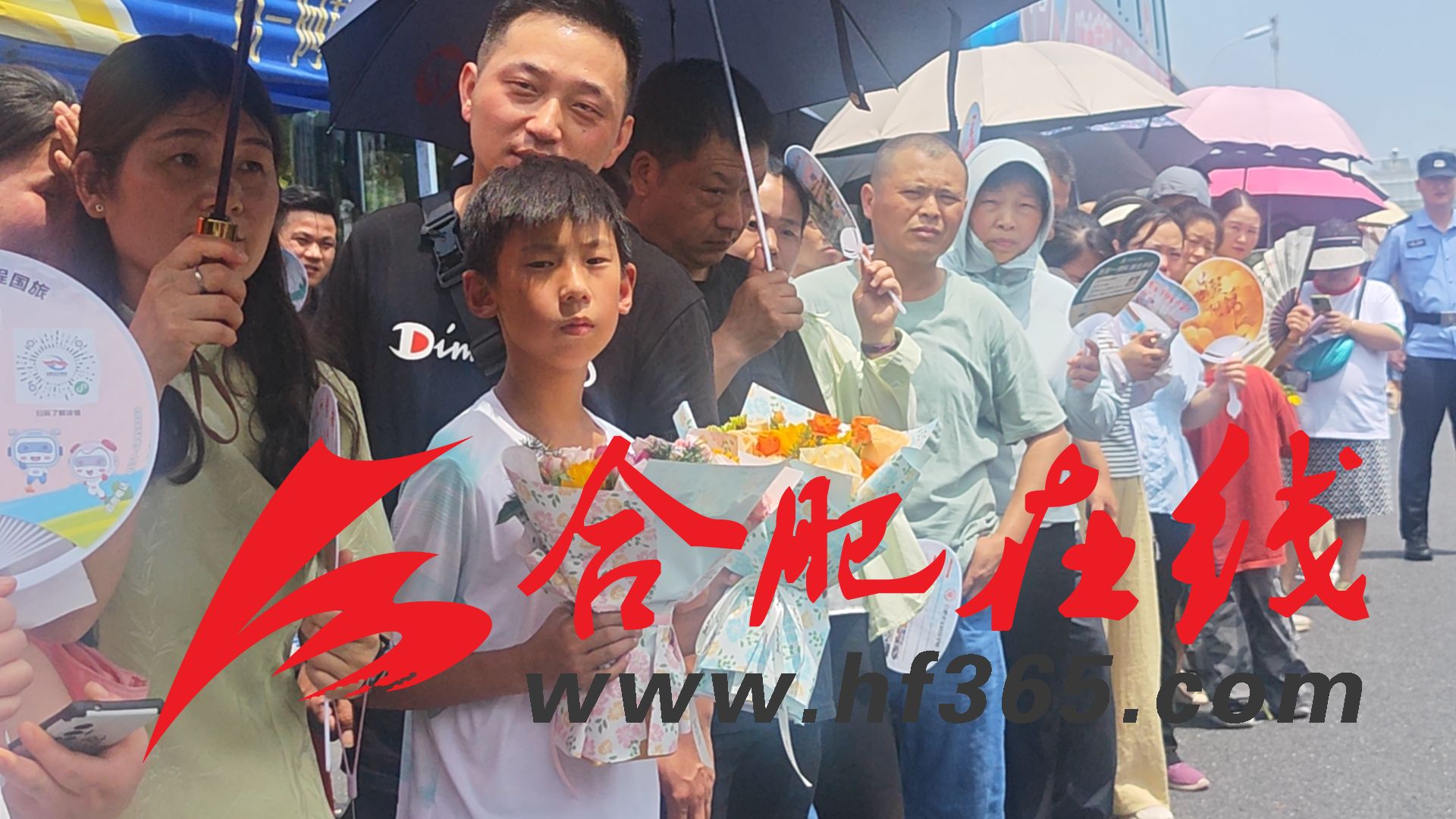 2025年6月14日,在合肥十中考点外,一名小朋友手持两束鲜花等待走出考场的哥哥和姐姐。杨锋/摄